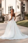 A woman wears the A1350 by Allure strapless white ball gown wedding dress with floral bodice embellishments, standing against a plain blue background.