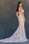 A woman stands gracefully against a plain dark background, wearing the C725 by Allure—a strapless, fitted white lace gown with floral detailing.