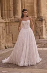 A woman stands outdoors in front of a stone building with columns, wearing product 63005A—a strapless lace wedding gown.