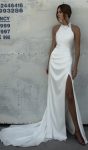 Flares Bridal + Formal | WALSH Woman models WALSH, a sleeveless white halter dress with a high slit, standing against a light-colored textured wall and gazing slightly to the side.