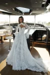Wearing VENICE, a long-sleeved lace wedding dress, a woman stands on the deck of a modern yacht.