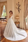 A woman wearing the 88504/MCKENNA wedding gown by Justin Alexander stands in an elegant room with wooden floors, arched doorways, and classic furnishings.