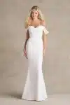 A woman stands against a neutral background wearing the R3989 by Allure, an off-the-shoulder, fitted white bridal gown featuring a subtle mermaid silhouette that exudes elegance.