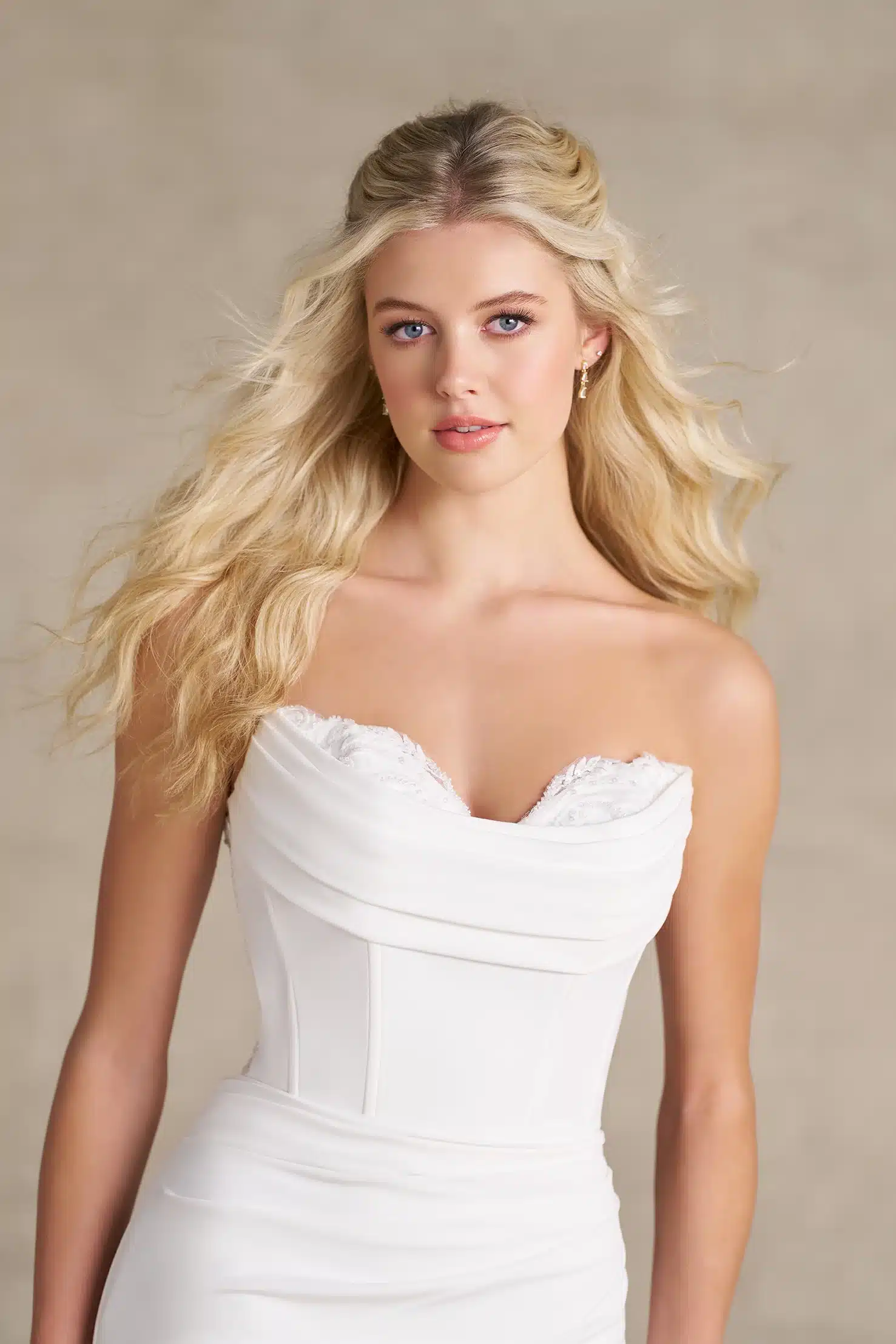 A woman with long blonde hair wears the strapless white R3989 wedding dress by Allure, standing against a neutral background and looking at the camera with a slight smile. A woman with long blonde hair wears the strapless white R3989 wedding dress by Allure, standing against a neutral background and looking at the camera with a slight smile.