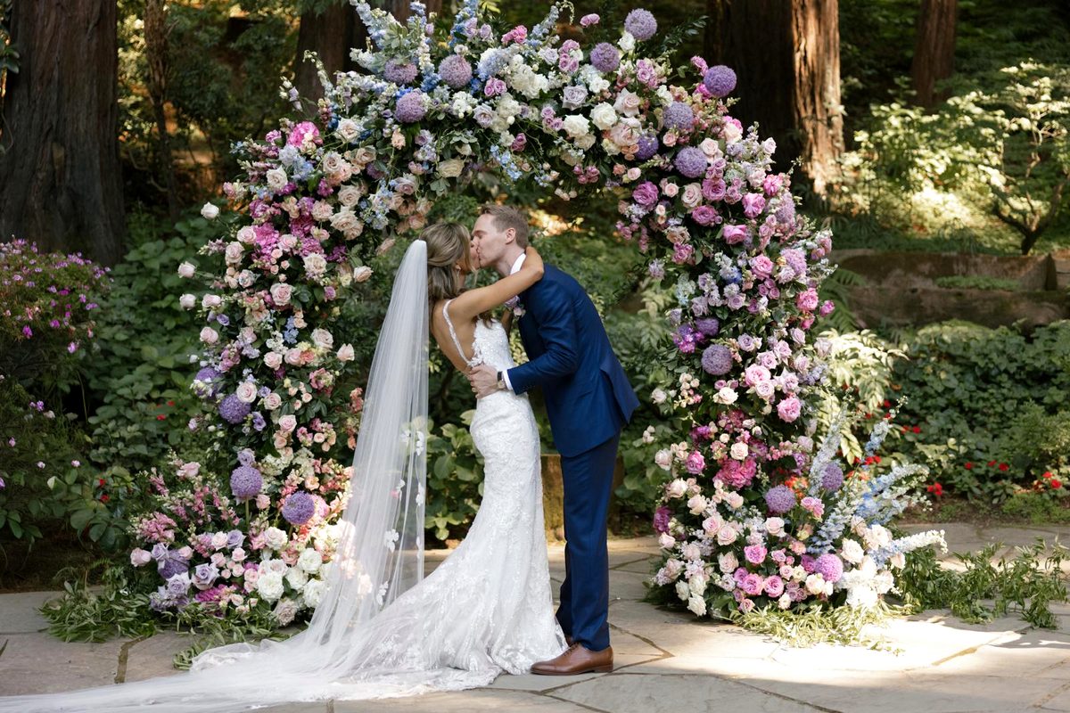 Outdoor wedding ceremony under a floral arch in the redwoods, Northern California