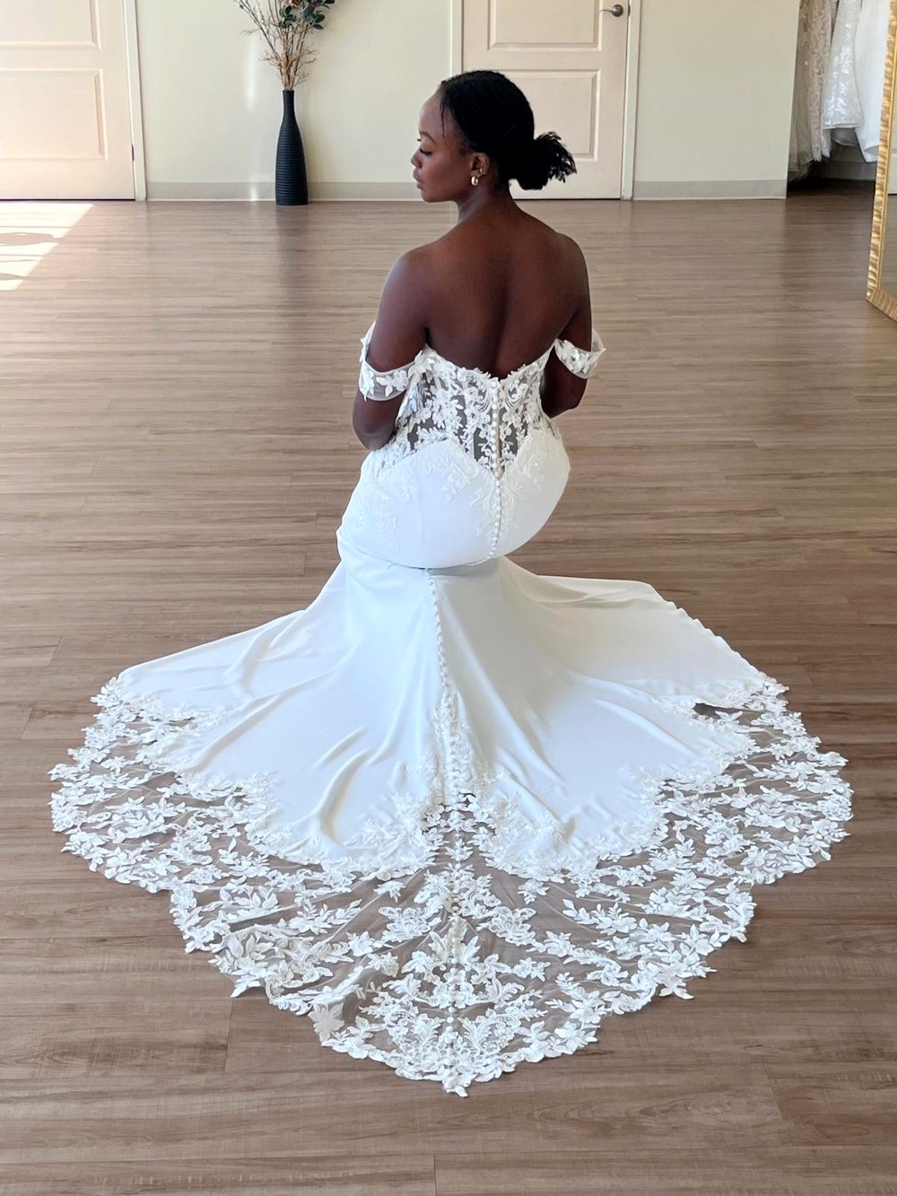 Bride trying on an off-the-shoulder lace wedding dress at Flares Bridal in Walnut Creek