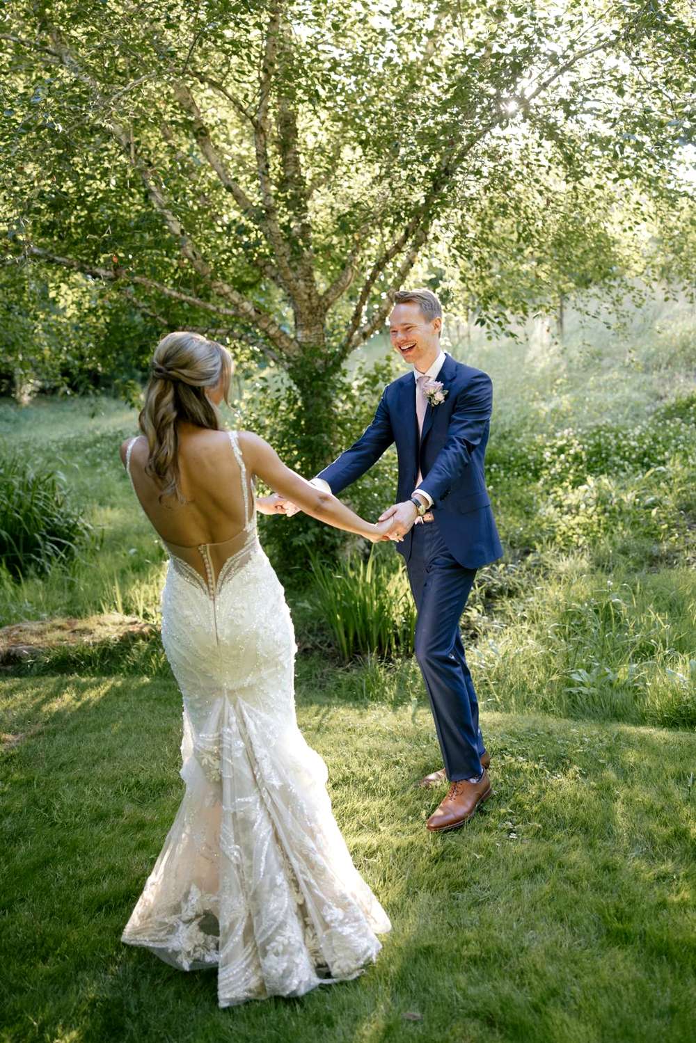 A bride in a fitted lace wedding dress with an open back
